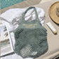 Dettaglio della borsa a rete personalizzata con scritta colorata sul pannello in cotone.