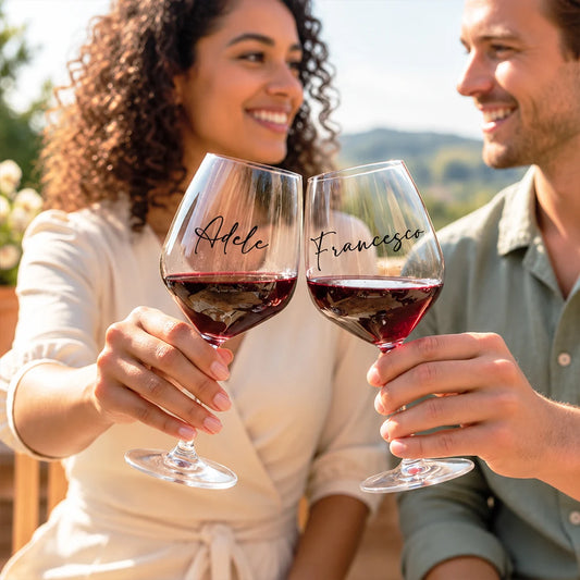 Coppia che brinda con calici da vino personalizzati con i nomi Adele e Francesco