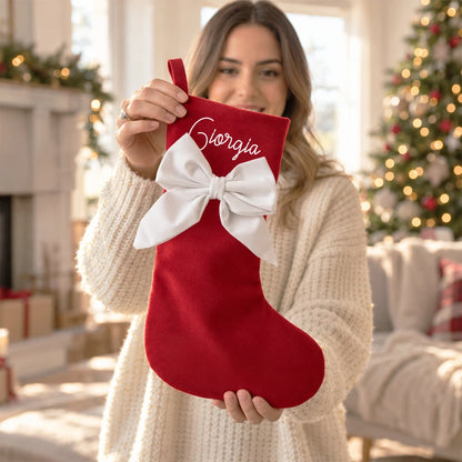 Calza di Natale rossa personalizzata con nome e fiocco bianco in mano a una donna