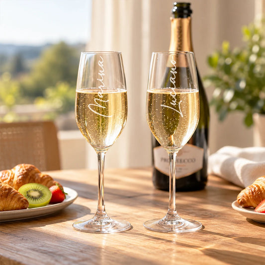 Due flute da prosecco personalizzati con i nomi Marina e Luciano con colazione sul tavolo