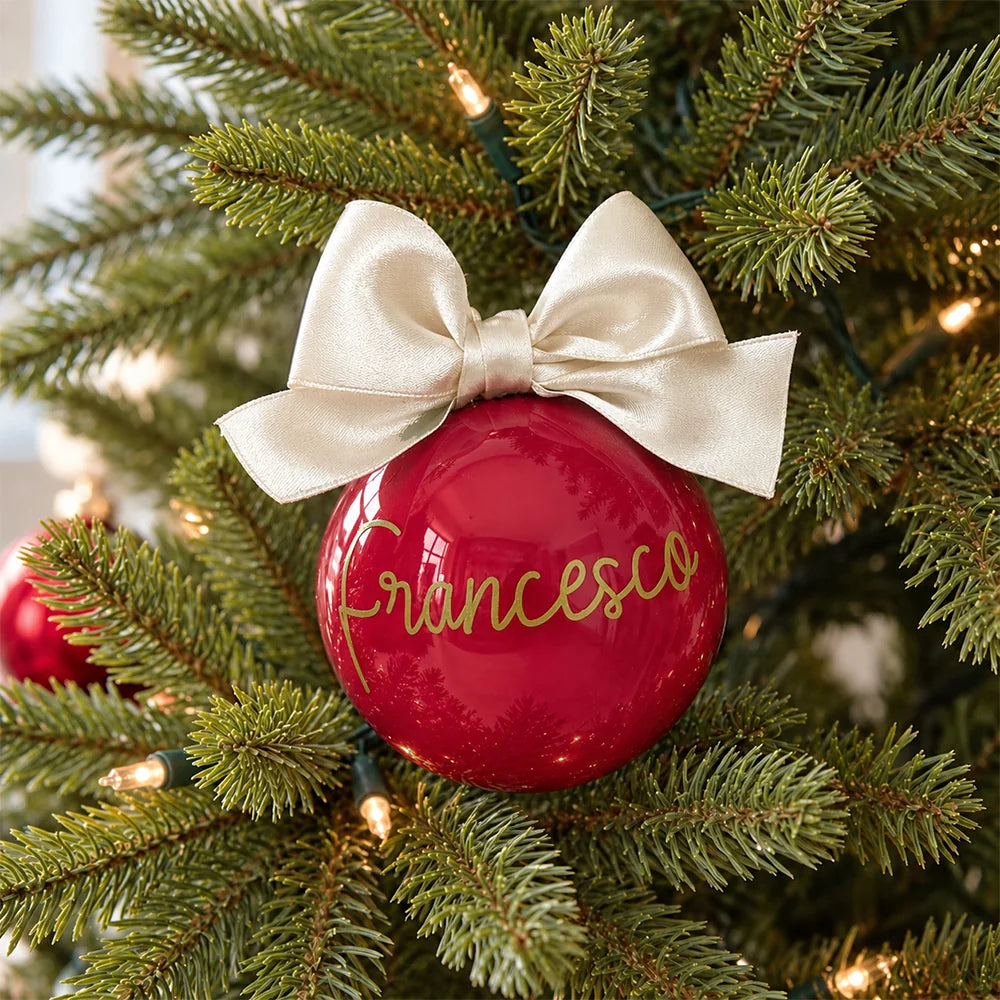 Sfera di Natale rossa personalizzata con nome in oro e fiocco avorio sull’albero