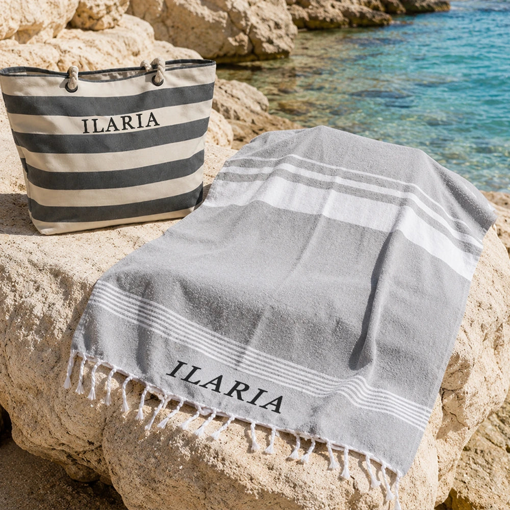Telo mare grigio coordinato con borsa mare a righe vicino al mare